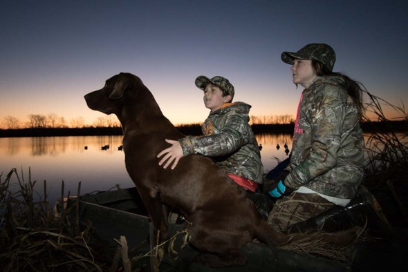 Brother and sister duck hunting with dog