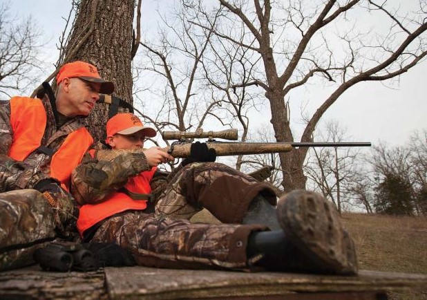 youth deer hunting by tree with dad