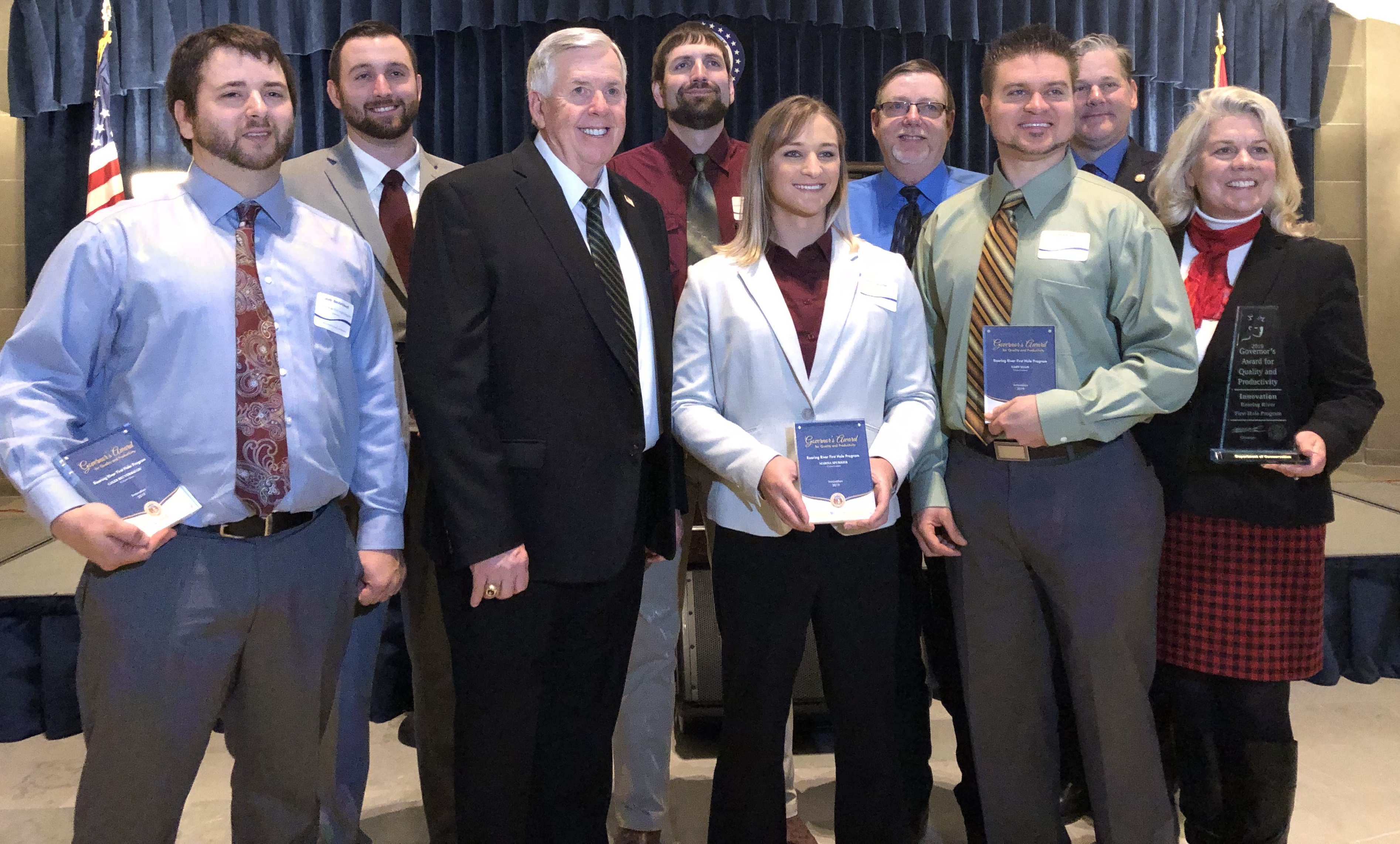 MDC Director Sara Parker Pauley poses with Governor Mike Parson and the Roaring River Fish Hatchery staff at the Missouri State Capitol.