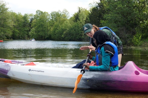 An MDC instructor teaches a girl how to kayak.