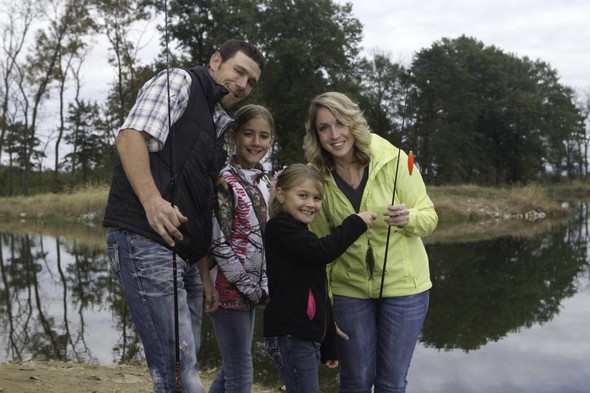 A family poses with a fish they caught on a fishing trip.