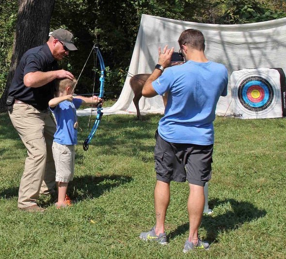 instructor showing kid how to shoot a bow