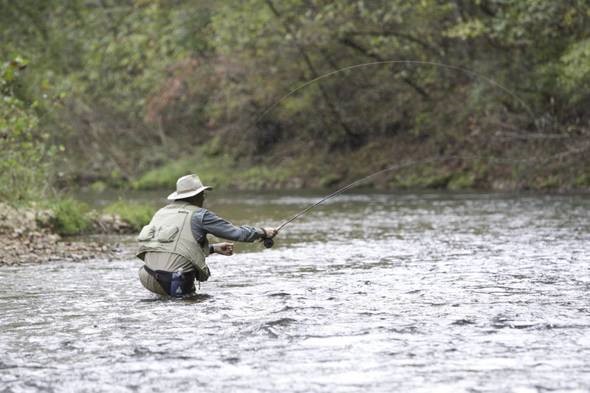 man trout fishing in stream
