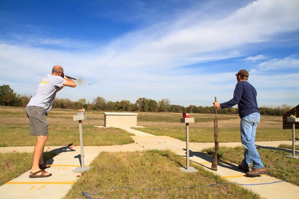 two men shoot shotguns at shooting range