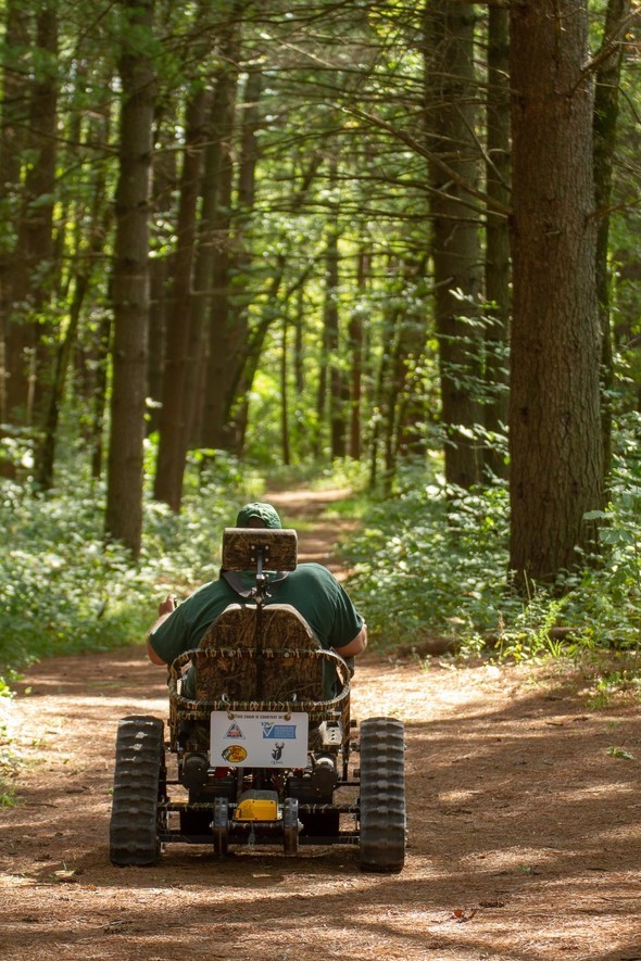 A man in an outdoor wheelchair hiking through the forest.