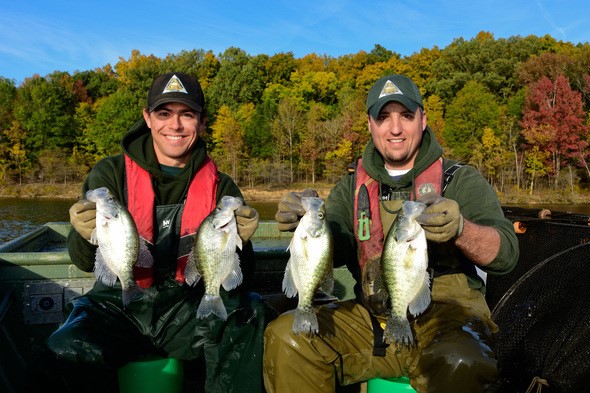 two MDC staff in boat each hold two crappie