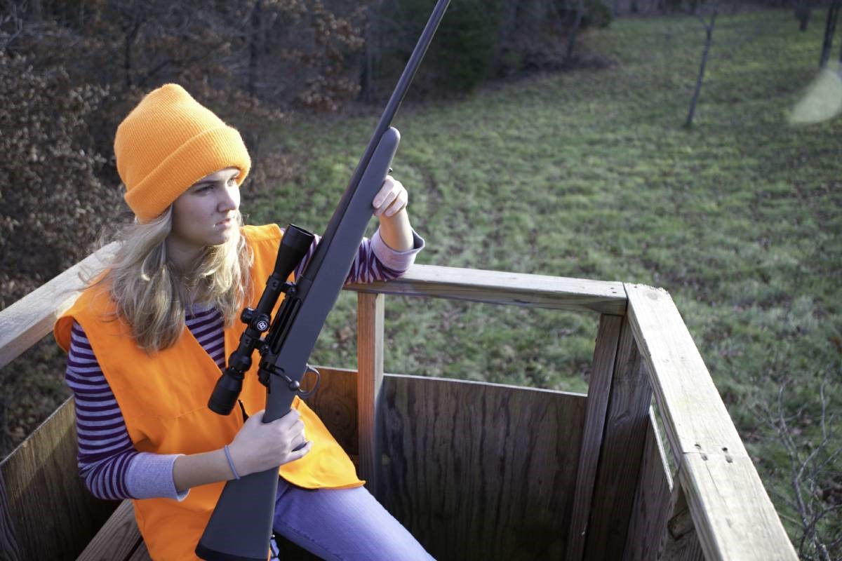 Woman in deer stand with rifle