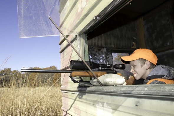 Young hunter aims rifle