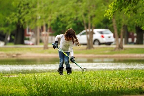 Young girl cleans up trash near a pond