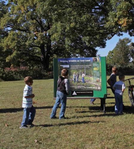 Kids reading a sign about wildlife.