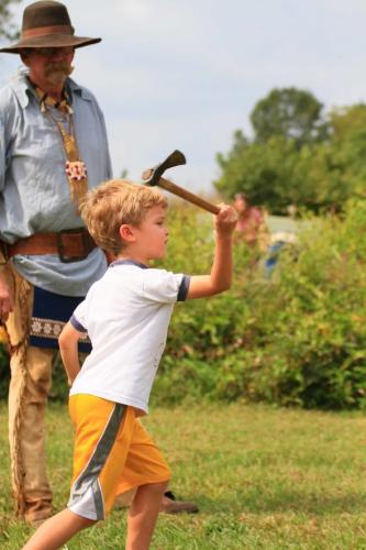 Boy throws a tomahawk a a target at Prairie day