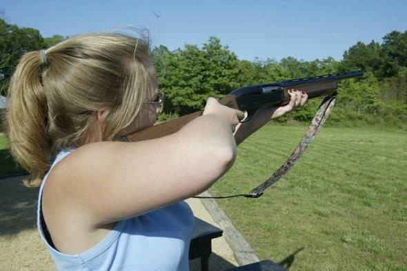 Woman shooting a shotgun.