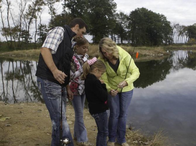 A family baits their fishing pole