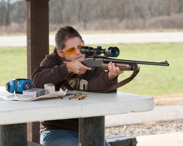woman shoots rifle at shooting range