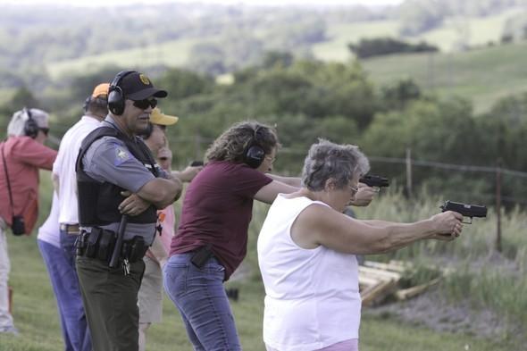 A conservation agent supervises a group of women during a handgun workshop.