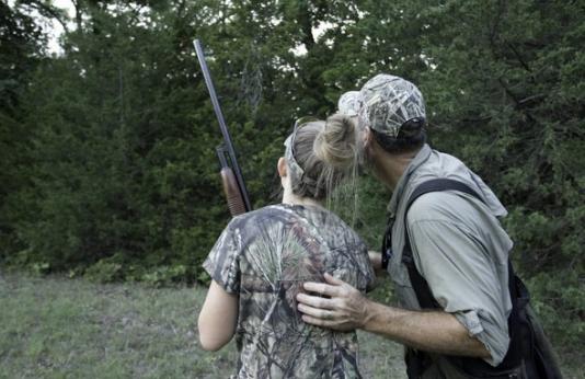 Father and daughter look for squirrels while hunting