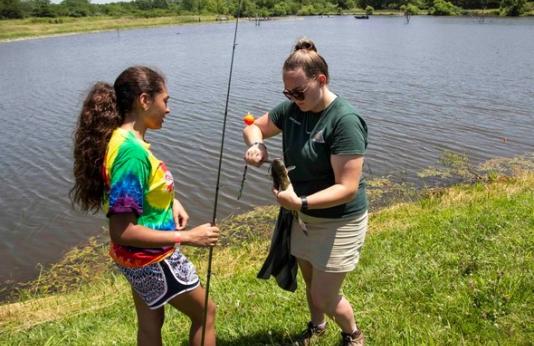 MDC staff member helps unhook a fish from teen's fishing line