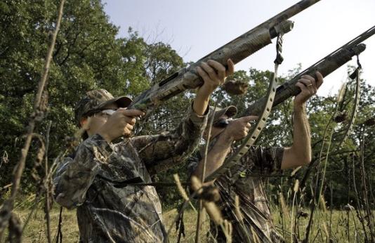 Two dove hunters aim shotguns to the sky