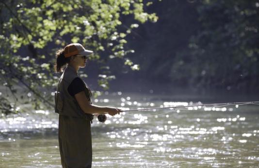 Woman fly fishing in stream