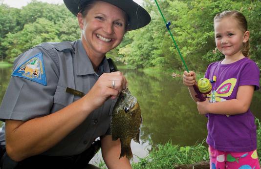 agent holding bluegill with girl angler in background
