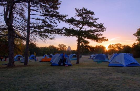 A field full of tents at sunset in Forest Park. 
