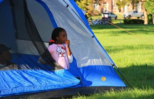 A child sitting in a tent in Forest Park.