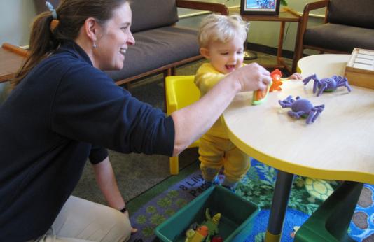 A mother plays with her toddler at a small table