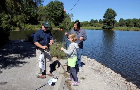 MDC staff person shows woman and girl how to fish. 
