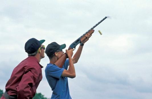 An MDC staff member teaches a teenager how to shoot a shotgun.