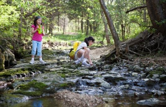 Two girls explore a creek outside of Runge Nature Center
