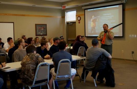 Instructor show how to handle a shotgun at a hunter education class.