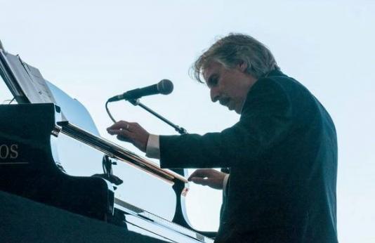 Composer and musician John Nilsen plays the piano at a music concert