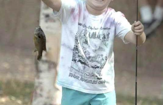 Little girl holding up a fish she caught.