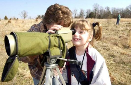 girl looks through spotting scope.