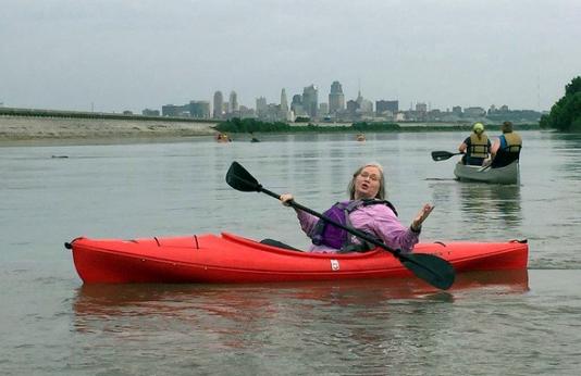 Woman in kayak on Missouri River with KC skyline in background