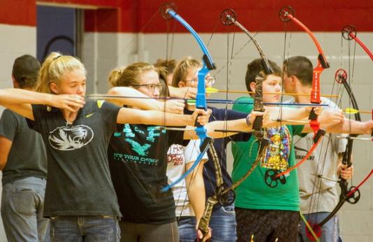 A group of students prepare to release their arrows during an archery class.