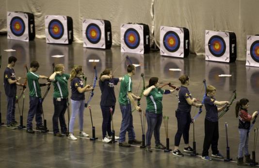Student archers in row shooting at NASP tournament