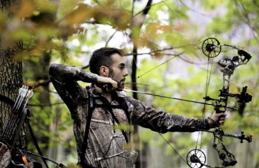 Archer draws bow in woods