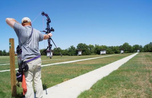 male archer shooting compound bow at target