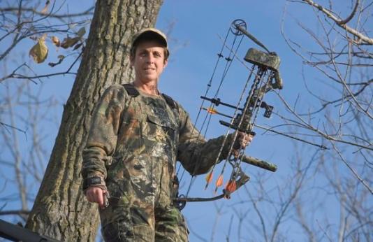 Bowhunter in full camo in a tree stand.