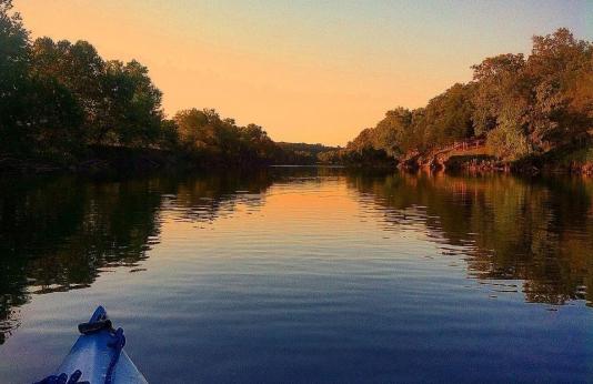 A kayak floats on the Gasconade River at sunset.