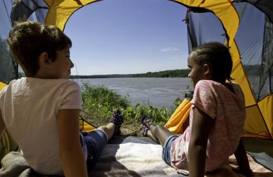 Kids sit in a tent while camping