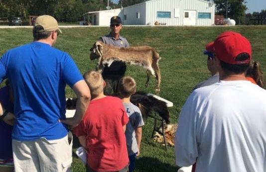 agent shows deer pelt to onlookers at outdoor presentation