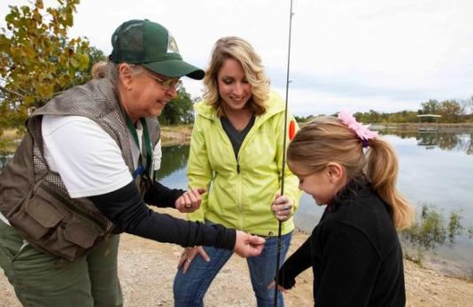 MDC staff help a mother and daughter bait a fishing hook