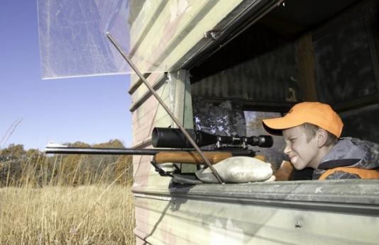 Young hunter aims rifle